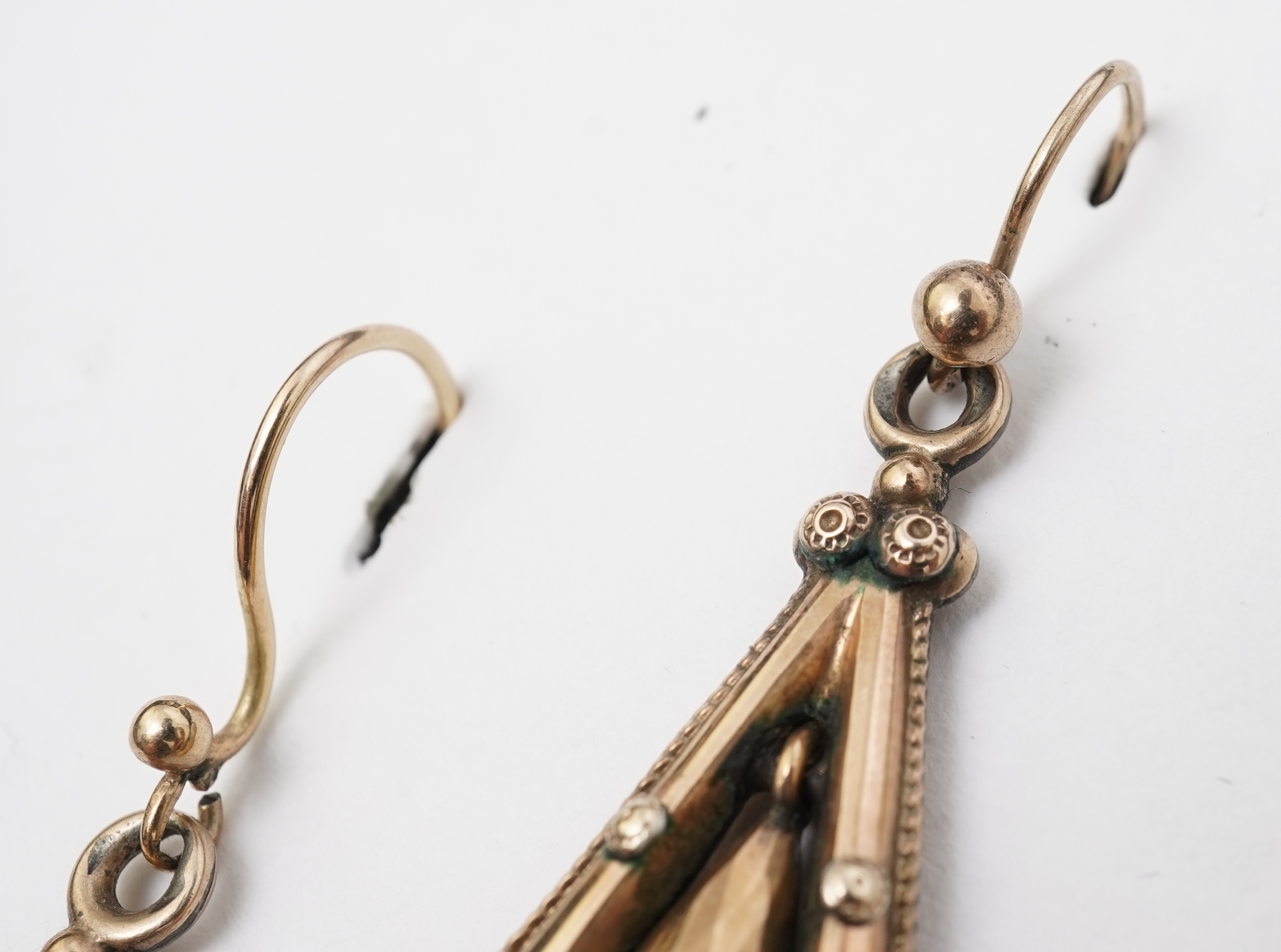 A pair of Victorian gold earrings, late 19th century, each of drop design, outlined with a rope twist border and accented with floral and foliate motifs, the centres suspending faceted pendants, length 5.8cm, one slightl